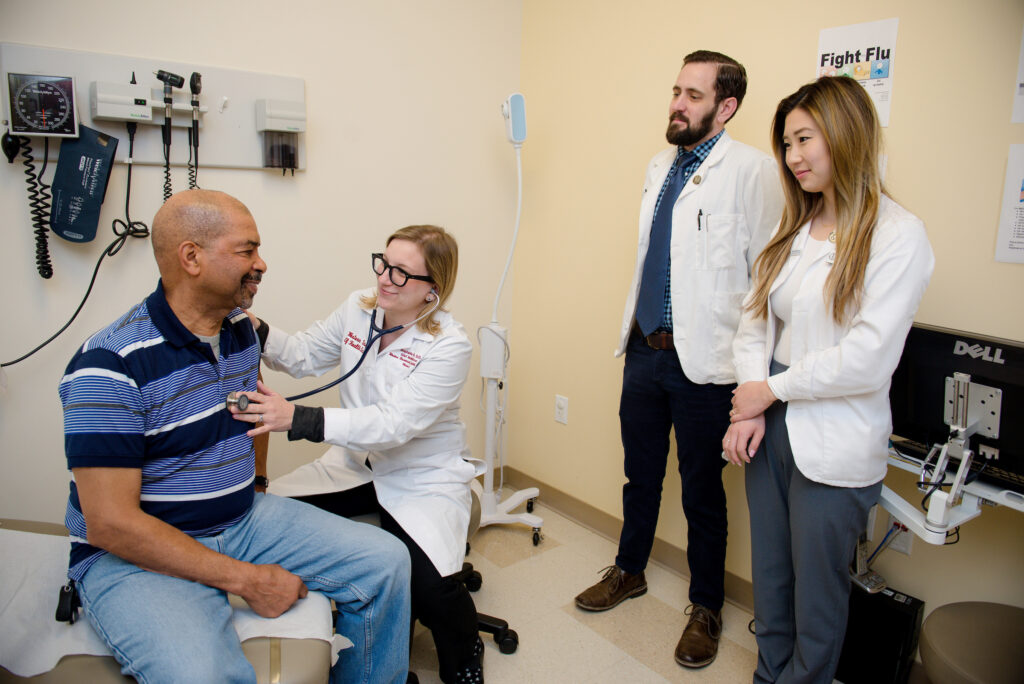 Doctor examines patient with medical students observing